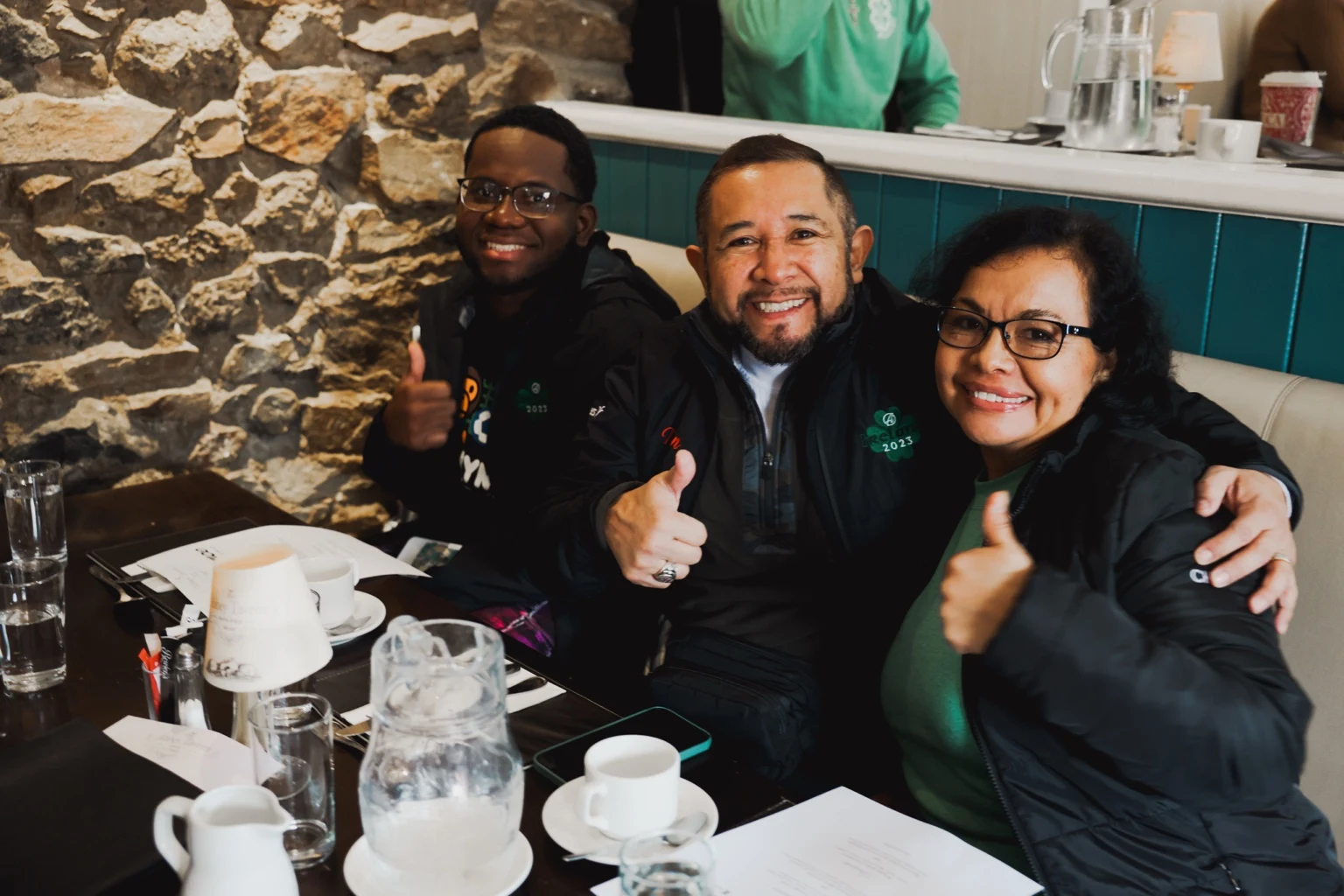 Three team members smiling together at a restaurant table