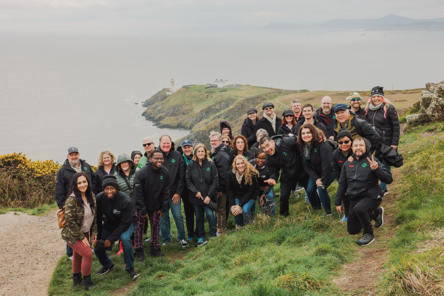 Team members posing on a green hillside above the sea
